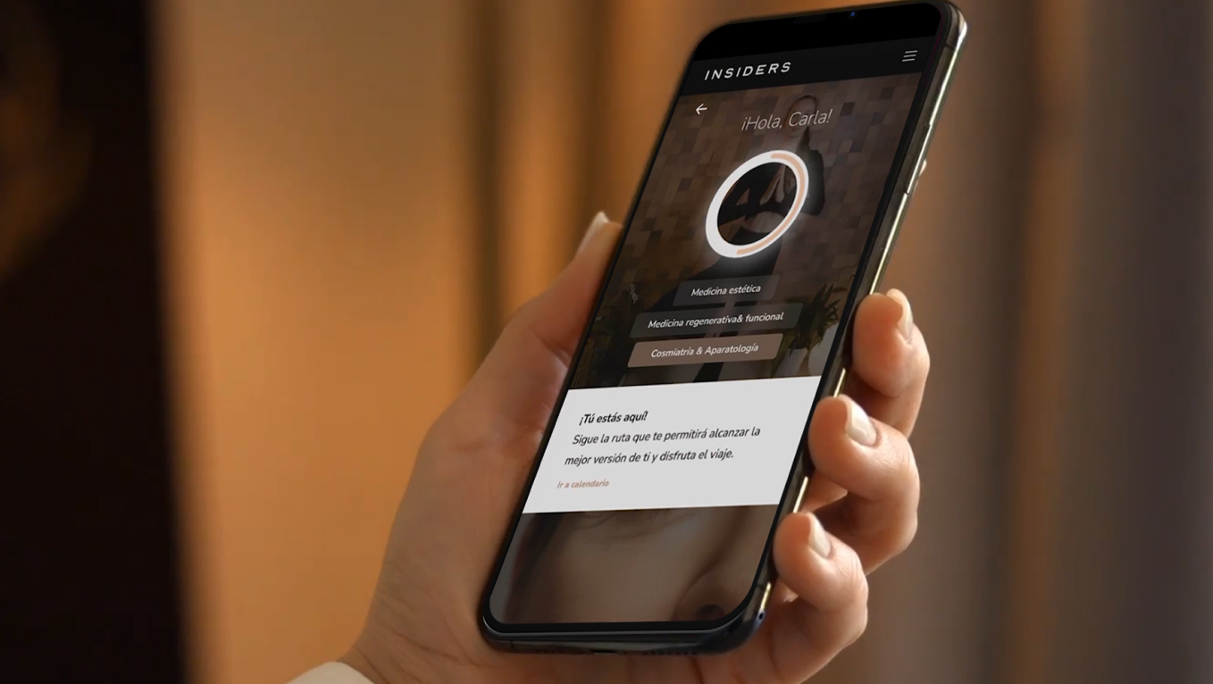 Persona sosteniendo un smartphone con una app interactiva de Insiders para personalización de servicios.